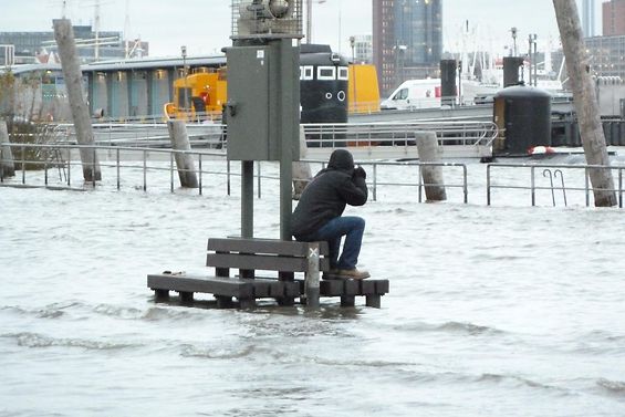 Die Elbe ist über ihre Ufer getreten. Auf einer Bank sitz ein Fotograf. Die Bank ist von Knie tiefem Wasser umspült.