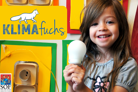 Ein kleines Mädchen hält eine Energiesparlampe in beiden Händen und lächelt in die Kamera.