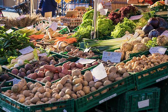 Wochenmarkt-Stand mit Gemüse, im Vordergrund stehen Kisten voller Kartoffeln