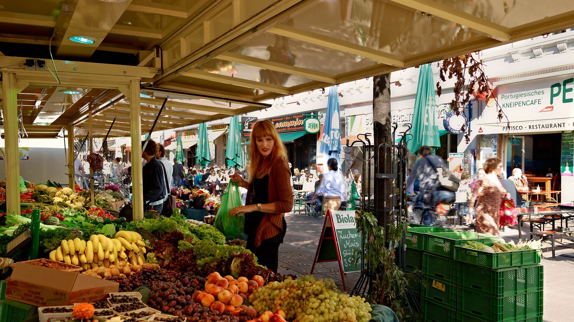 Rothaarige Frau kauft an einem Wochenmarkt-Stand auf dem Hamburger Schulterblatt ein 